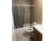 Bathroom with tiled shower-tub and patterned shower curtain, tile floor and dark wood vanity at 5129 Chandler Way, Denver, CO 80239
