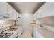 Galley kitchen with white cabinets and gas stove at 4412 W Pondview Dr, Littleton, CO 80123