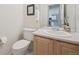 Powder room featuring wood vanity, framed mirror, and white toilet at 604 S Yarrow St, Lakewood, CO 80226