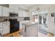 Bright kitchen features white cabinets, stainless steel appliances, and an island with tile countertops and sliding glass doors at 604 S Yarrow St, Lakewood, CO 80226