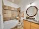 Well-lit bathroom featuring stone tile, modern fixtures, tub, and round mirror at 383 S Franklin St, Denver, CO 80209