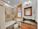Bathroom featuring stone tile, wood frame window, granite counter and vanity lights at 383 S Franklin St, Denver, CO 80209