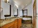 Well-lit bathroom with double sinks, a soaking tub, and stone tile flooring at 383 S Franklin St, Denver, CO 80209