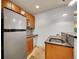 Charming kitchenette with stainless fridge, wooden cabinets, tiled backsplash, and open counter space at 383 S Franklin St, Denver, CO 80209