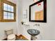 Stylish powder room with a unique vessel sink, a framed mirror, a decorative light fixture, and natural wood trim at 383 S Franklin St, Denver, CO 80209