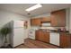 Functional kitchen with wood cabinets, white appliances, and laminate flooring at 2565 S Sheridan Blvd # 14, Lakewood, CO 80227