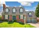 Charming brick home featuring a lush front lawn, dormer windows, and an attached two-car garage at 7193 S Newport Way, Centennial, CO 80112