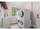 Convenient laundry room with sink, wooden shelf, and stacked washer and dryer on a built-in platform at 9871 Indian Wells Dr, Lone Tree, CO 80124