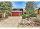 Charming home showcasing a red garage door, driveway, stone accents, and mature trees at 15740 Sandtrap Way, Morrison, CO 80465