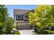 Two-story home features a stone facade, two car garage, and beautiful trees on a sunny day at 16404 E 117Th Ave, Commerce City, CO 80022