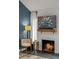 Close-up of the fireplace with white brick, rustic mantel, and a cozy chair at 14252 E Radcliff Cir, Aurora, CO 80015
