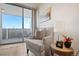 Sunlit living room features a comfy armchair and access to a private balcony with city views at 909 N Logan St # 10C, Denver, CO 80203