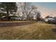 Expansive backyard with lush lawn and mature trees, framed by a brick retaining wall and leading to a pool at 7382 W Stanford Ave, Littleton, CO 80123