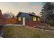 Charming pool house featuring dark siding, brick base, white trim and front door, nestled in a landscaped yard at 7382 W Stanford Ave, Littleton, CO 80123