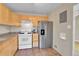 Cozy kitchen featuring wood cabinets, stainless steel fridge, and standard white appliances at 1658 Winona Ct, Denver, CO 80204