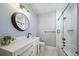 Stylish bathroom featuring a modern vanity, round mirror, and a shower-tub combination with glass door at 2732 S Jackson St, Denver, CO 80210
