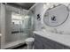 Beautiful bathroom featuring updated vanity with gray cabinets, a round mirror, and glass enclosed tiled shower at 2452 S Norfolk St, Aurora, CO 80013