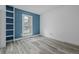 Spare bedroom features hardwood style floors, a built in bookcase, a bright blue accent wall, and a large window at 2452 S Norfolk St, Aurora, CO 80013