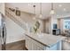 Open layout showcases a kitchen with white cabinetry, island, and modern lighting at 17153 W 91St Ln, Arvada, CO 80007