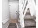 A staircase leads downstairs with gray carpeted stairs and a white railing; an entry door is visible at the bottom at 15045 E Louisiana Dr # B, Aurora, CO 80012