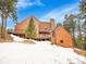 Rear exterior view of the home showing a red door, deck, and wooded surroundings at 23485 Bluestem Dr, Golden, CO 80401