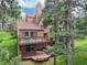 Back exterior featuring an elevated deck, a lower patio with a hot tub, and a beautifully wooded yard at 23485 Bluestem Dr, Golden, CO 80401