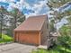 Exterior view of detached garage with wooden door, a ramp, stone foundation and a brown roof at 23485 Bluestem Dr, Golden, CO 80401