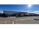 Commercial building featuring a blue roof, glass windows, and ample parking on a clear day at 495 Bennett Ave, Bennett, CO 80102