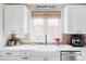 Bright kitchen featuring white cabinets, quartz countertops, apron sink and stainless steel dishwasher at 680 S Ogden St, Denver, CO 80209