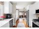 Long bright kitchen with white cabinets, stainless steel appliances, hardwood floor leading to the living room at 680 S Ogden St, Denver, CO 80209