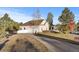 View of garage with two bays and long driveway with adjacent trees and shrubs at 34427 Columbine W Trl, Elizabeth, CO 80107