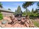 Backyard patio featuring red pavers, Adirondack chairs, small fire pit, and a hot tub in the background at 1570 Blakcomb Ct, Evergreen, CO 80439