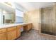 Bathroom featuring double sinks, a glass shower, wood cabinets, and neutral tiling at 9522 Silver Spur Ln, Highlands Ranch, CO 80130