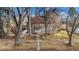 Brick home with tile roof, mature trees, and a black metal fence at 1650 Monaco St Pkwy, Denver, CO 80220