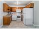 Compact kitchen featuring wood cabinets, white appliances, tile flooring at 9155 E Center Ave # 3C, Denver, CO 80247