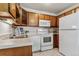 Charming kitchen featuring wood cabinets, white appliances, and a stylish backsplash at 9155 E Center Ave # 3C, Denver, CO 80247