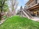 Landscaped backyard with a lush lawn, wooden fence, and stairs leading to the deck above at 62 N Ranch Rd, Littleton, CO 80127