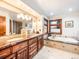 Luxurious bathroom with double vanities, marble countertops, and a soaking tub by a window at 62 N Ranch Rd, Littleton, CO 80127