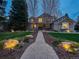 A long walkway leads to a home with professional landscaping and exterior lighting at twilight at 62 N Ranch Rd, Littleton, CO 80127
