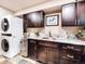 Well-organized laundry room with dark cabinetry, stainless steel sink, granite counters, and stacked washer and dryer at 62 N Ranch Rd, Littleton, CO 80127