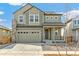 Charming two-story home with an attached two-car garage and stone details against its light green facade at 9293 Biscay St, Commerce City, CO 80022