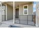 Inviting front porch with sleek, black railings and modern light fixture accent the home's entrance at 9293 Biscay St, Commerce City, CO 80022