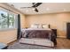 Cozy bedroom featuring a comfortable bed, ceiling fan, large window and neutral colored walls at 805 Northridge Rd, Highlands Ranch, CO 80126