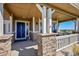 Inviting covered front porch with stone columns, a blue front door and scenic views at 2351 Sagebrush St, Parker, CO 80138