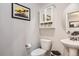 Cozy powder room featuring a pedestal sink, toilet, and a mirrored cabinet for storage at 4885 S Algonquian Way, Aurora, CO 80016