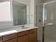 Bathroom with wooden cabinets, white countertops, a large mirror, and glass-enclosed shower at 2025 Barnwood Dr, Brighton, CO 80601