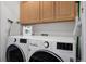 Laundry room with a washer, dryer, and wooden cabinets at 9771 Mayfair St # F, Englewood, CO 80112
