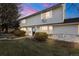 Two-story home with a gray exterior, stone accents, manicured lawn and garden, and a beautiful sunset at 6920 Navajo St # B, Denver, CO 80221