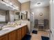This primary bathroom features double sinks, wood cabinetry, and a glass enclosed shower at 8240 Clayton Ct, Denver, CO 80229