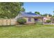 Exterior view of well-maintained home showcasing solar panels, fenced yard, and landscaped lawn at 6995 W 27Th Ave, Wheat Ridge, CO 80033